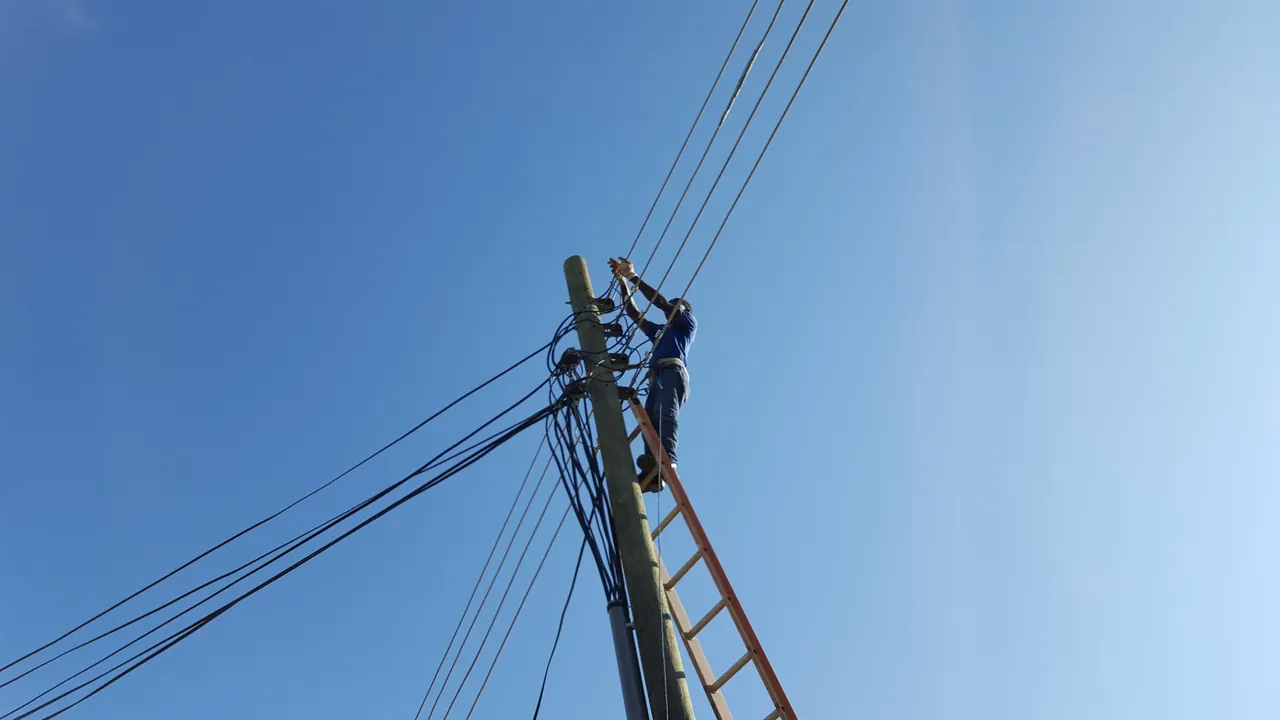 Électricien au travail sur un poteau, photo réelle de chantier.