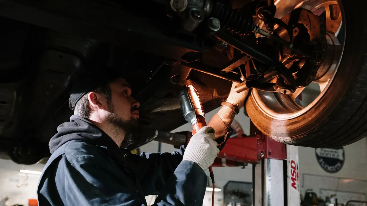 Mécanicien au travail sous un véhicule, dans un garage.