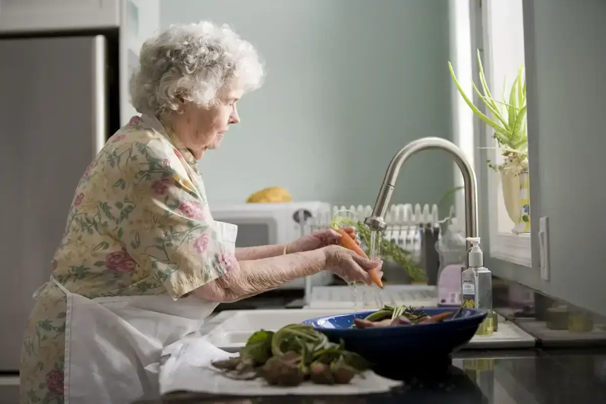 Une dame âgée prépare des légumes à sa cuisine