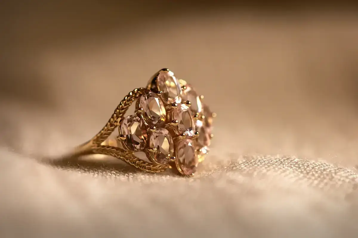 Bague en or ornée de pierres roses sur un tissu beige