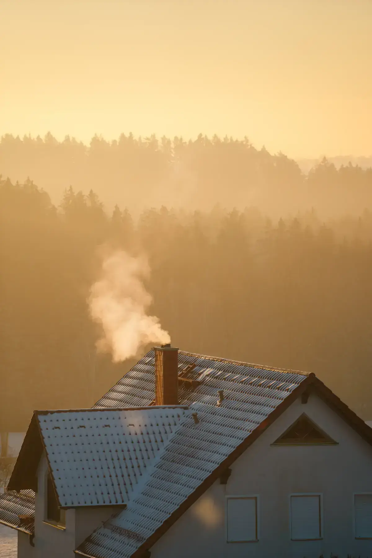 Maison dont la cheminée fume au lever du jour