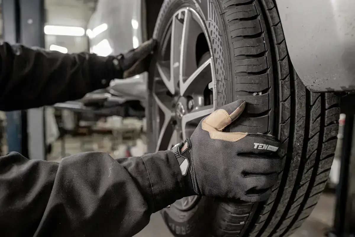 Mains gantées sur un pneu dans un atelier
