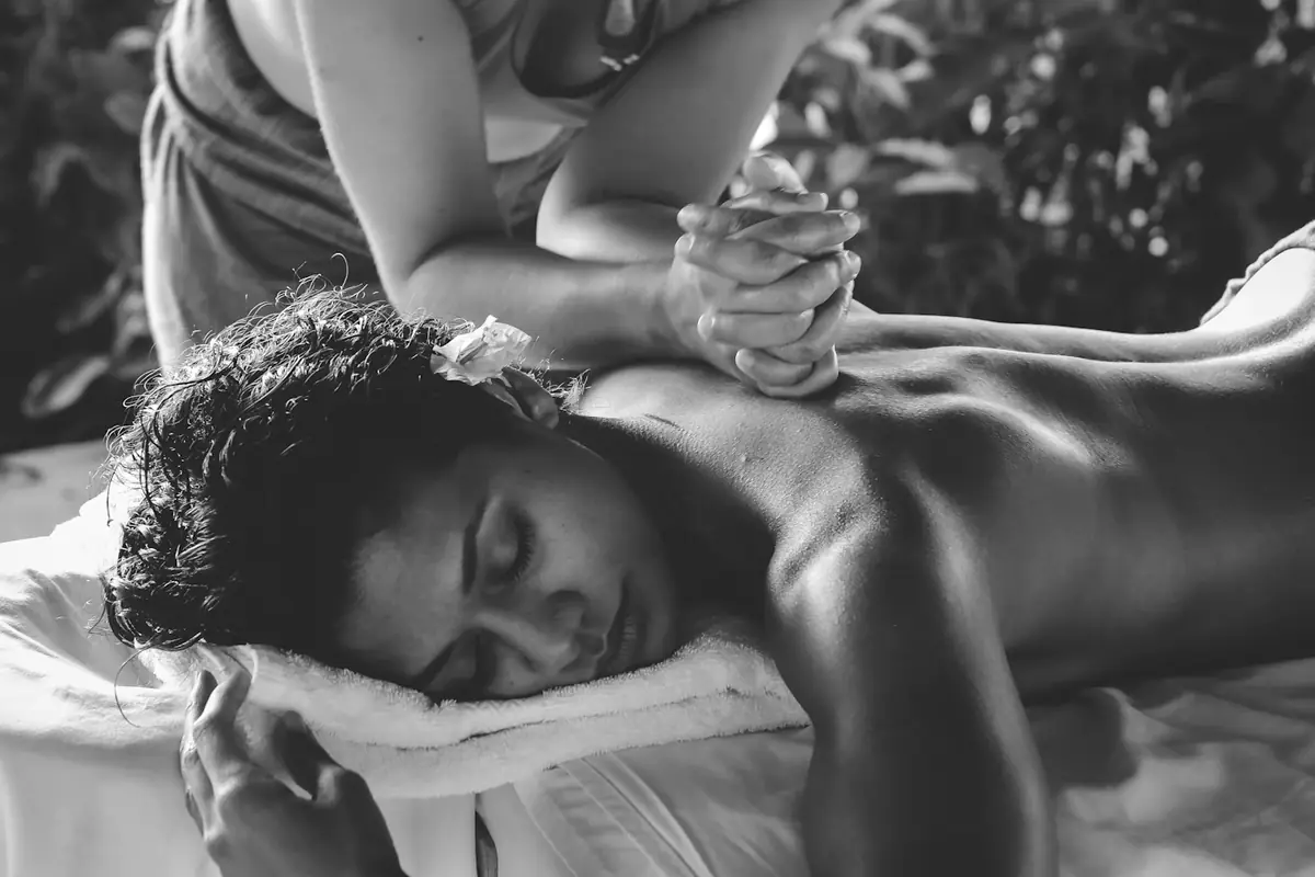 Personne allongée qui reçoit un soin du dos, en noir et blanc