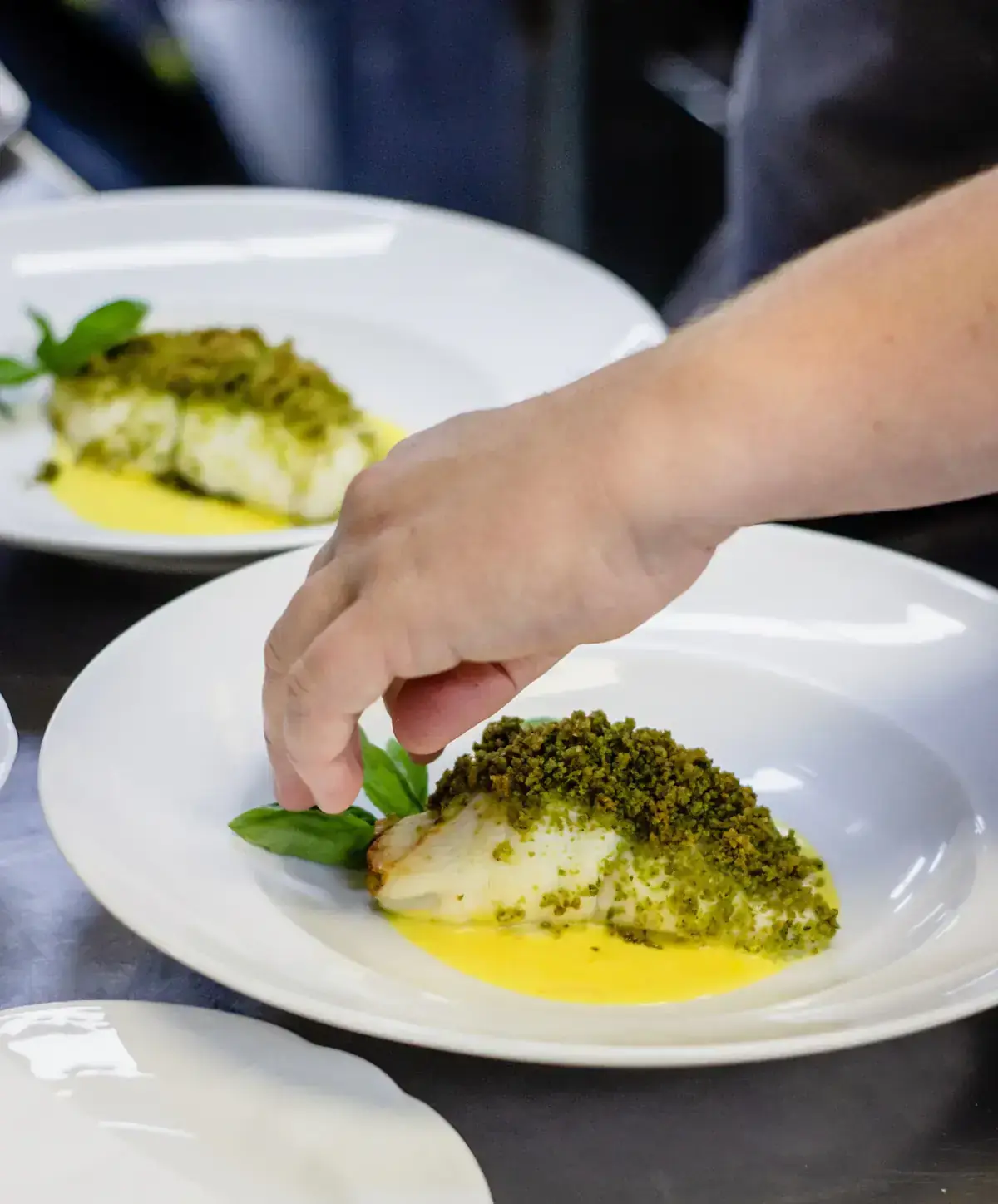 Chef qui dresse un poisson en croûte d’herbes