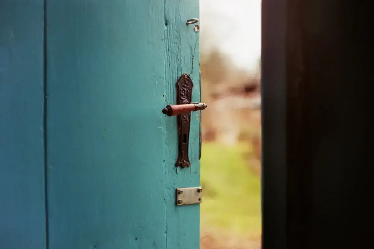 Porte turquoise entrouverte avec sa serrure ancienne